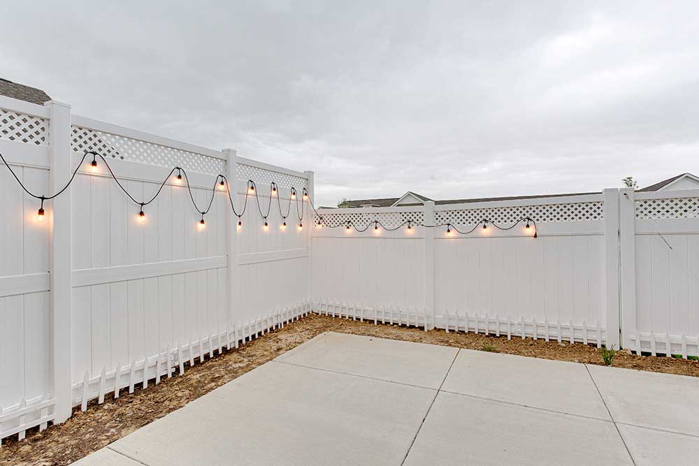 String of lights on vinyl white fencing concrete patio